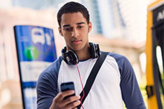 Male wearing headphones and looking at phone