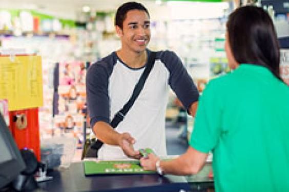 Shop assistant handing green concession go card to male customer