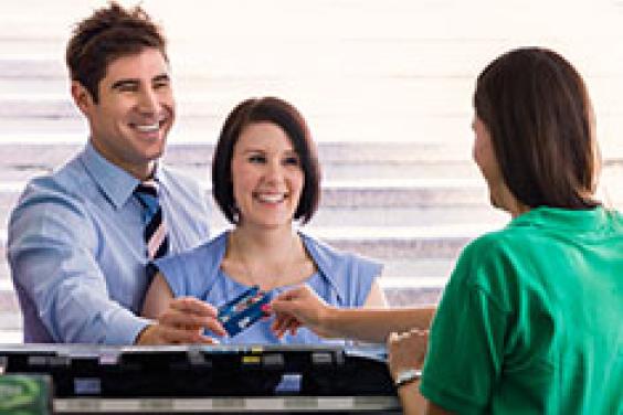 Male and female handing blue adult go card to assistant in a store